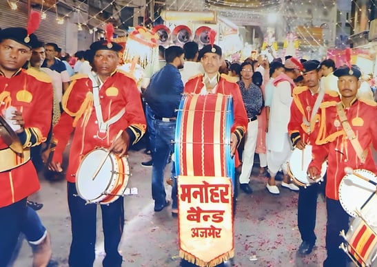 An old photo of the Manohar Brass Band playing clarinet, thap dhol, nagara drum, and shehnai instruments.