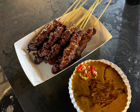 sate or chicken skewers with peanut sauce on the side with chillies in it