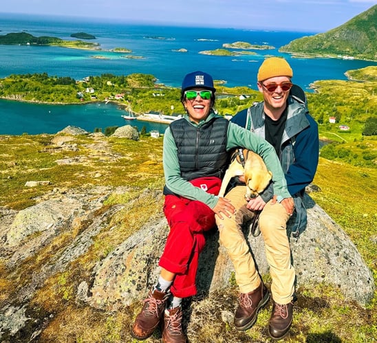 a man and woman sitting on a rock in the mountains of the Lofoten islands | Island hopping