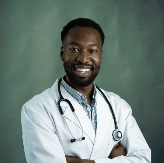 Médico negro sorrindo, com estetoscópio no pescoço e braços cruzados.