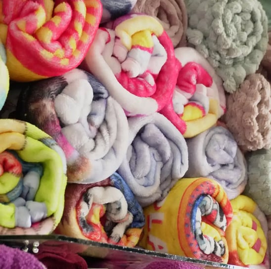 Una fila apilada de diferentes estilos de cobijas en la tienda.