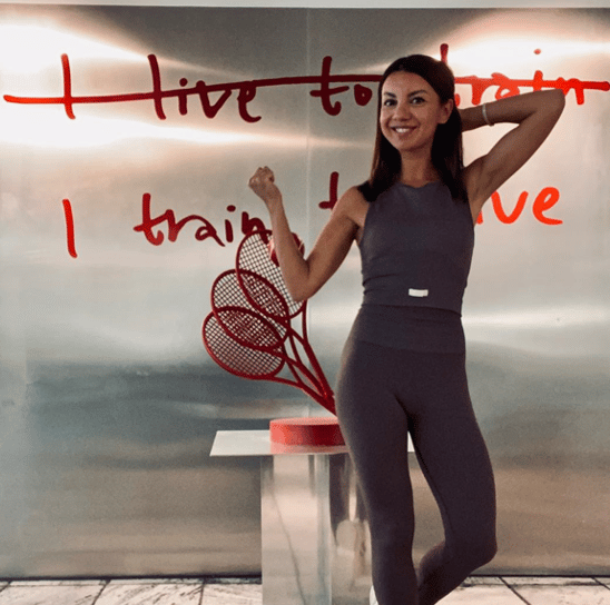 a woman in a gray top and leggings and a tennis racket
