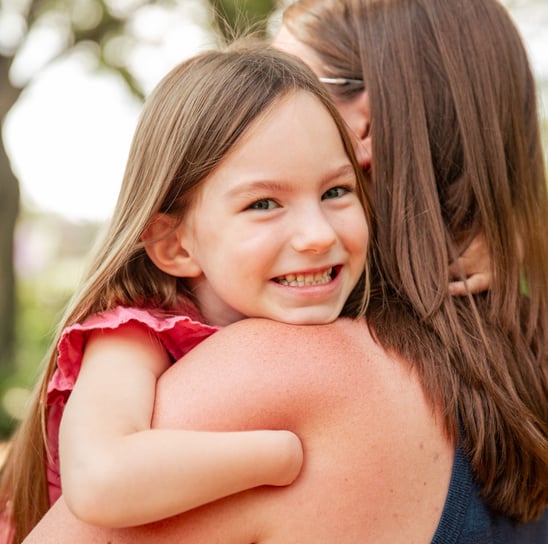 Young smiling girl with arm that stops at wrist hand and hugging a woman 