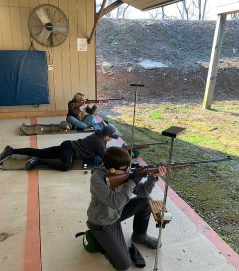 a man and woman are shooting rifles in a shooting range