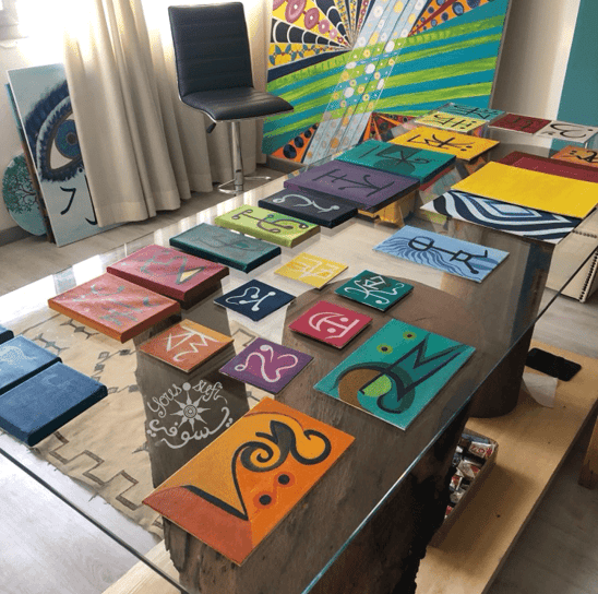 glass table covered in Yous’ small paintings