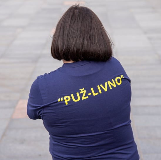 a woman in a blue shirt is holding a cell phone