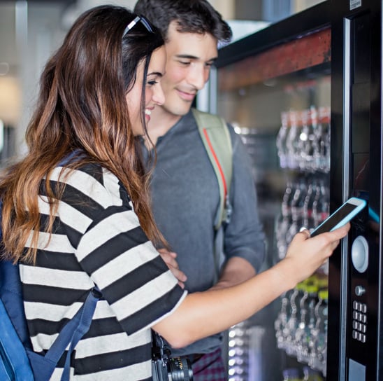 A couple usint tap to pay to make a vending machine purchase