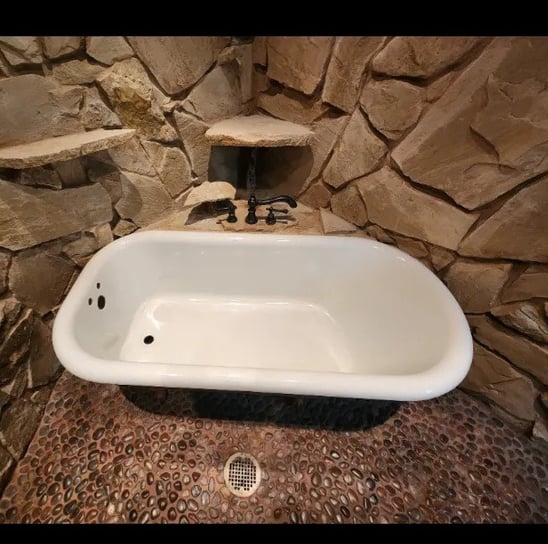 a clawfoot tub refinished in white with a stone wall in tyler texas