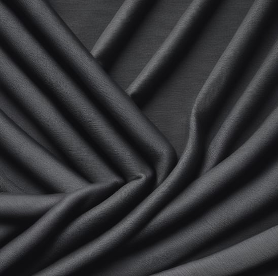 A close-up view of a denim fabric with prominent stitching details. A small red tag with black text is visible, partially showing a brand name. The fabric texture and stitching are clearly defined, illustrating the quality and craftsmanship of the material.