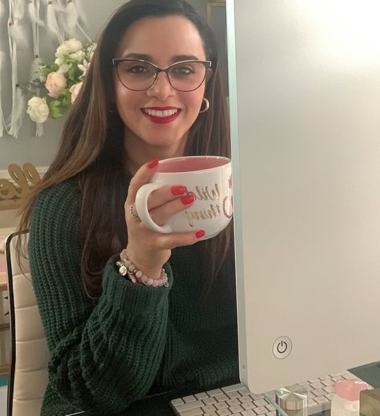 a woman sitting in front of a computer holding a mug