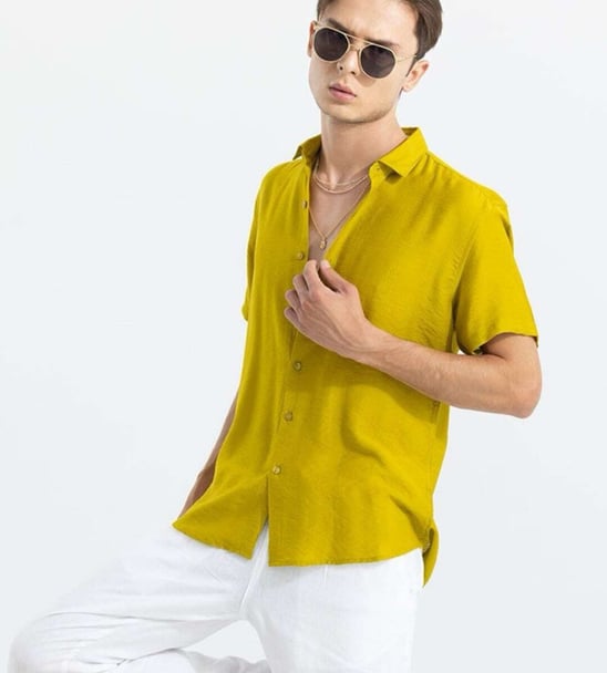 a man in a yellow shirt and white pants