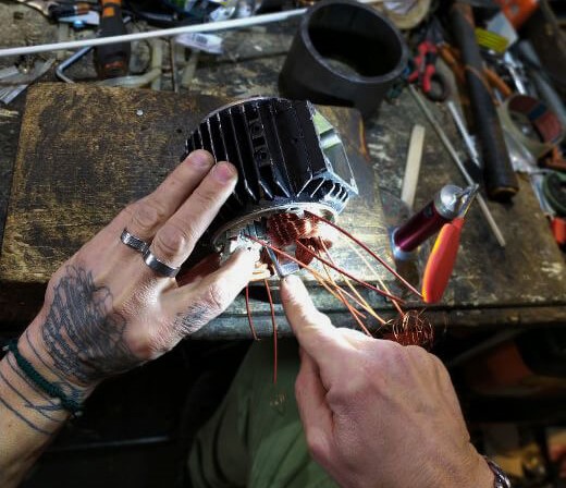 Riparazione di un motore elettrico, nella foto sono presenti due mani che riparano un motore