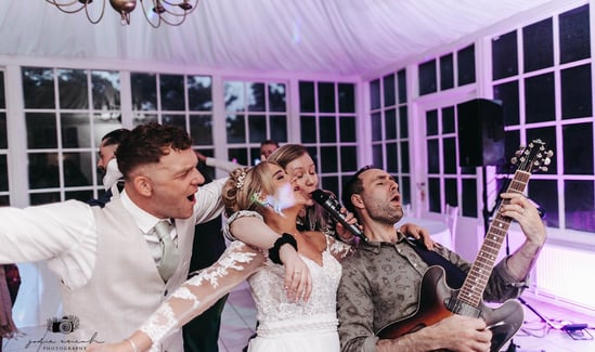 Bride and groom having fun with wedding singer musicians and band