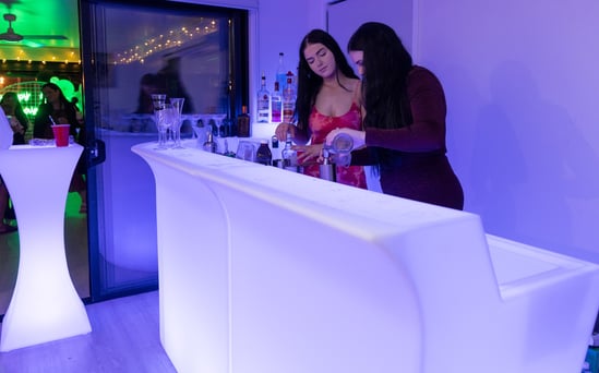 LED glow bar hire setup in Redlands for vow renewal, featuring cocktail table and two bartenders mixing drinks