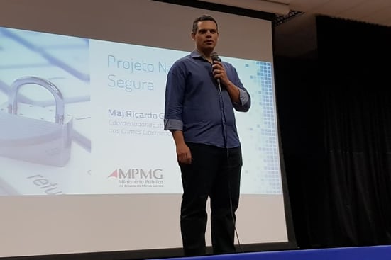 Homem em pé realizando uma palestra para uma plateia
