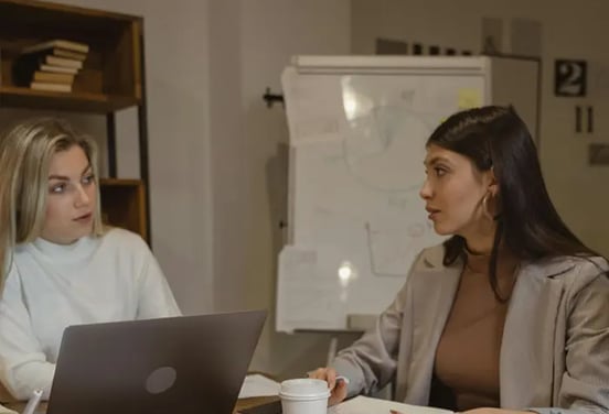 une cheffe d'entreprise discute avec une des ses employées pour faire un sondage du team building