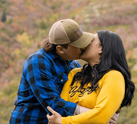 a man and woman kissing in the mountains