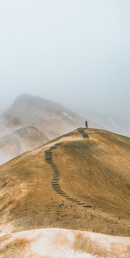 Une personne en haut d'une montage, elle a réussi à parcourir tout le chemin
