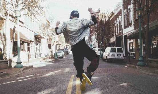 a man in a gray shirt is dancing while walking in down a street