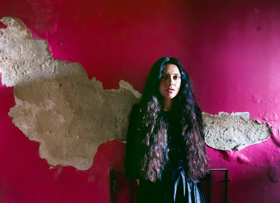 a woman in a black dress standing in front of a pink wall