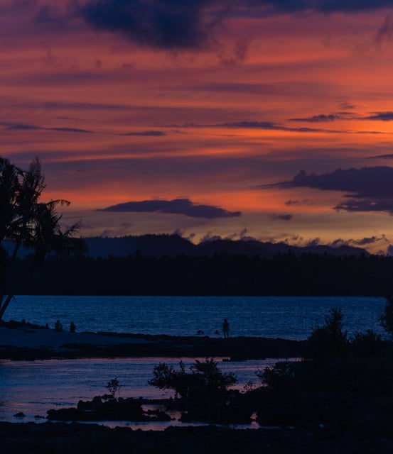 a sunset with a lone bird flying over a body of water