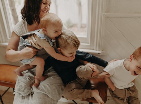 a woman holding a baby and two children