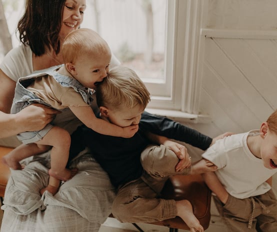 a woman holding a baby and two children