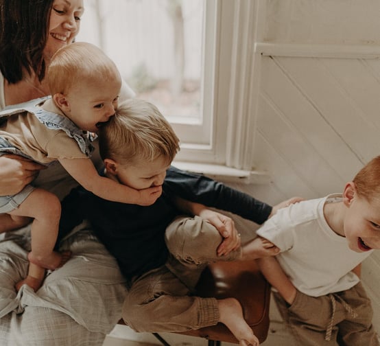 a woman holding a baby and two children