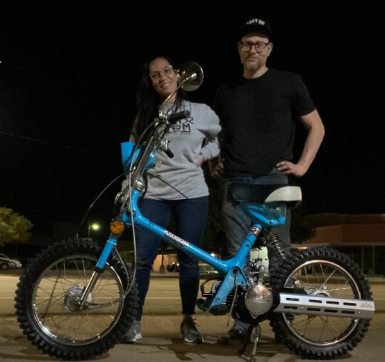 woman and man standing behind Honda scooter