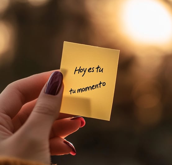 Mano femenina sostiene nota con frase "Hoy es tu momento", representa inspiración y empoderamiento para emprender.