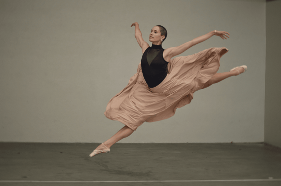 a woman dancing in a dress and a black top.