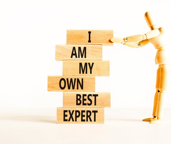 figure holding a pile of wooden blocks. Word on blocks spell I Am My Own Best Expert