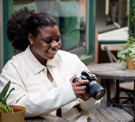 a black woman smiling in white jacket looking at outdoor photography photos