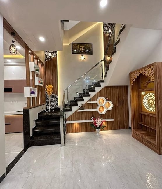 A modern staircase with wooden and glass accents, featuring elegant decor and a dedicated pooja spac