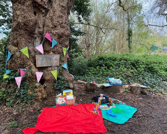 A blanket with books and sensory toys in an outdoor book nook