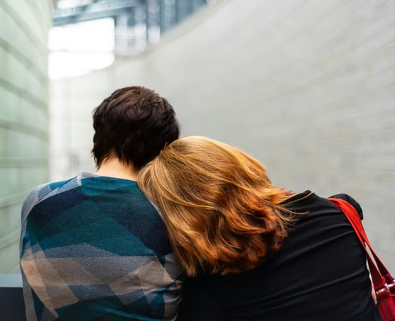 a man and woman sitting on a bench in a city