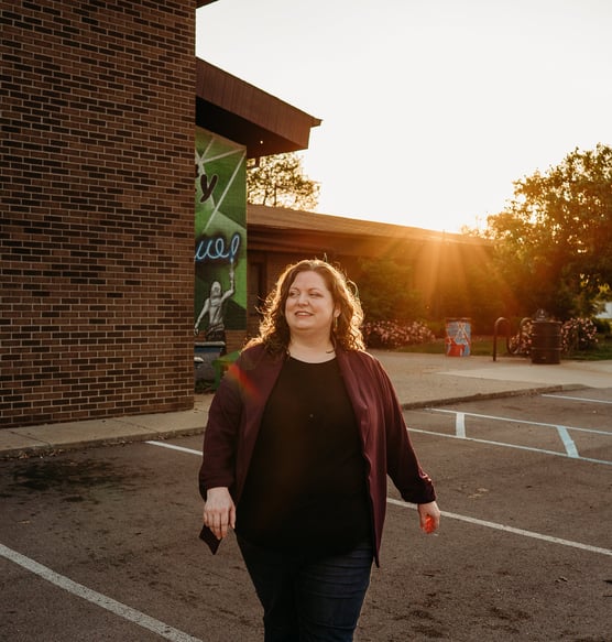 Confident woman walking with community center in background