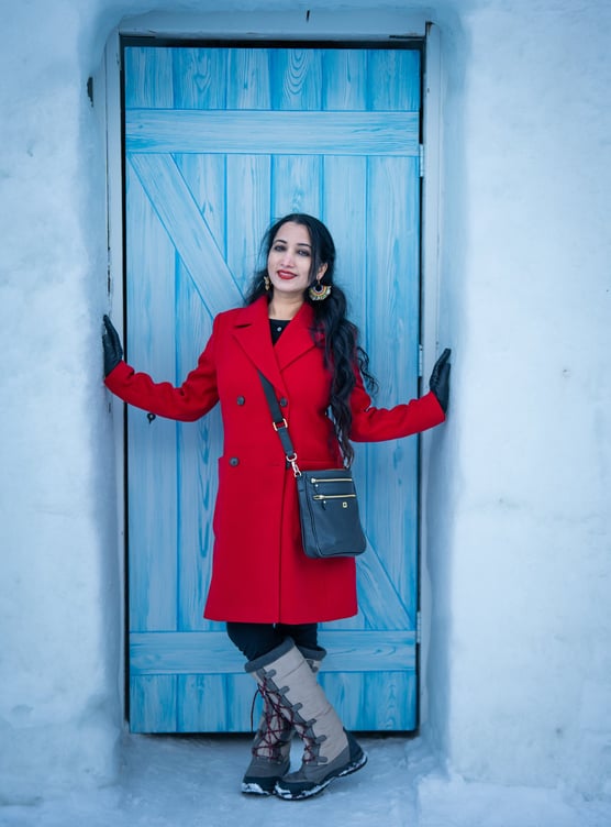 a woman in a red coat and boots standing in front of a blue door