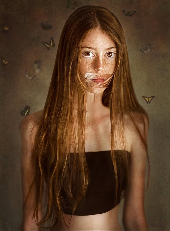 Surreal conceptual photography of a freckled young woman with emotional expression, butterflies and a mysterious storytelling