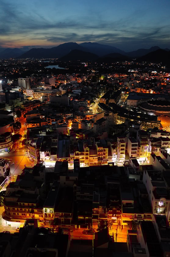Night aerial view of Nha Trang with city lights and mountains - By ACAT Photos