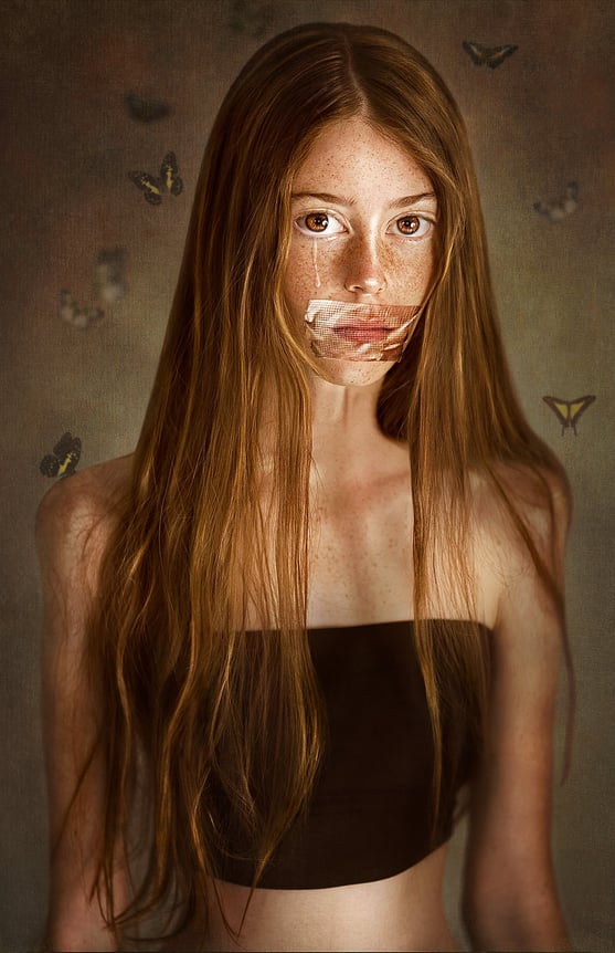Surreal conceptual photography of a freckled young woman with emotional expression, butterflies and a mysterious storytelling