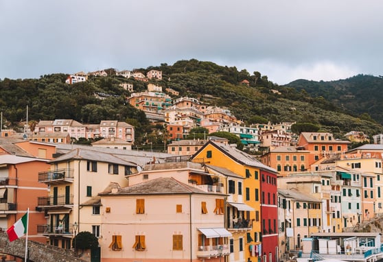 Hillside view of colorful houses in Bogliasco - with lush greenery - Italian flag in the foreground
