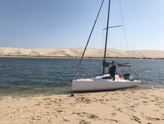 a man standing on a beach with a sailboat