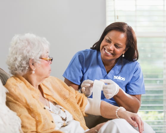A healthcare worker helping an elderly patient with a wound dressing