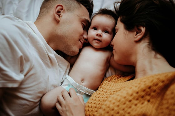 An image of two parents showing attention and nurture towards their baby in a secure attachment