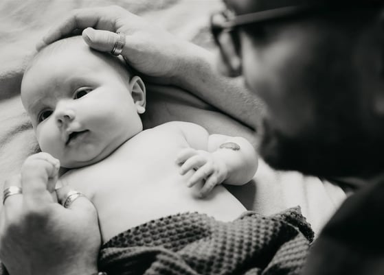 Papa protège tendrement son bébé avec ses mains – photo naissance à domicile dans le Gard