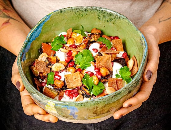 a woman holding a bowl of Lebanese food