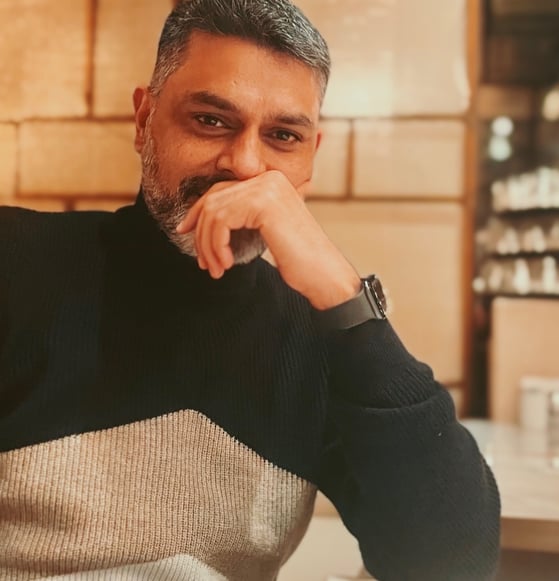 Author and Poet Himayath Khan sitting on a couch smiling