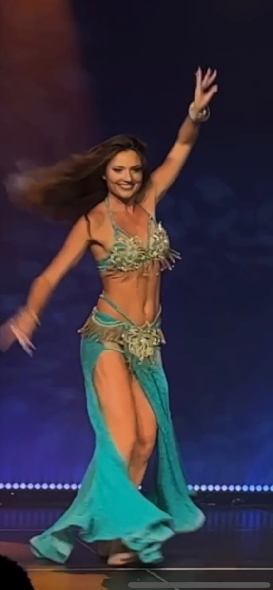 On stage in a turquoise costume under blue light