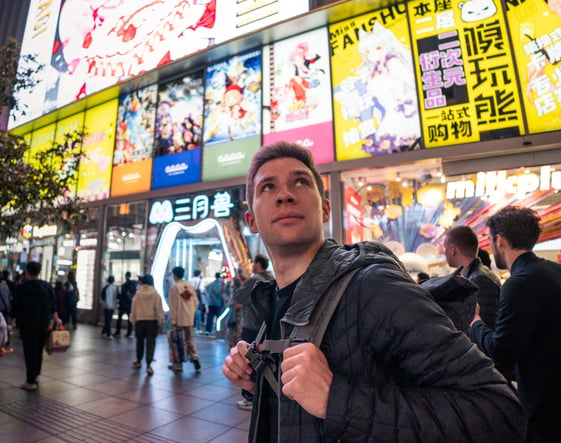 a man standing in front of a building with a backpack on his back